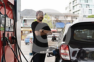 Portrait of a smiling businessman refueling his luxury car at the gas station. Man driver hand refilling and pumping gasoline oil