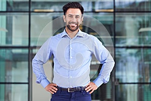 Portrait Of Smiling Businessman Standing In Lobby Of Busy Modern Office photo