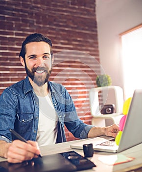 Portrait of smiling businessman using graphic tablet and laptop