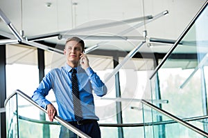 Smiling businessman using smartphone while standing at office