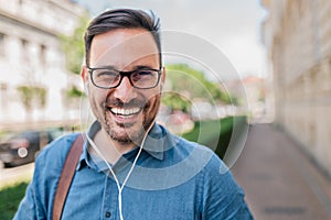 Portrait of smiling businessman wearing eyeglasses listening music on headphones