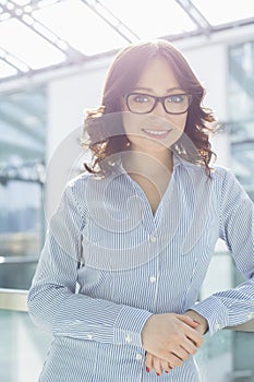 Portrait of smiling businesswoman leaning on railing in office