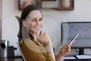 Portrait of smiling businesswoman sit at workplace holds smart phone