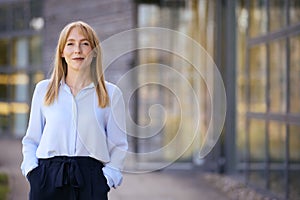 Portrait Of Smiling Businesswoman Standing Outside Modern Office Building