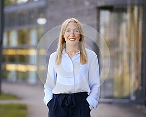 Portrait Of Smiling Businesswoman Standing Outside Modern Office Building