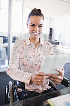 Portrait of smiling businesswoman using digital tablet while sitting on wheelchair