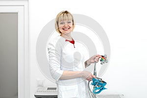 Portrait of smiling cardiologist holds the electrocardiograph sensors in his hands before connecting them to the system