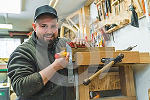 Portrait of smiling carpenter measuring a wooden board with angle ruler and pencil