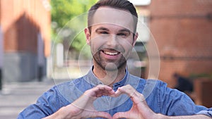 Portrait of Smiling Casual Man Gesturing Heart with Hand