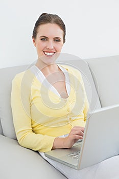 Portrait of a smiling casual woman using laptop on sofa