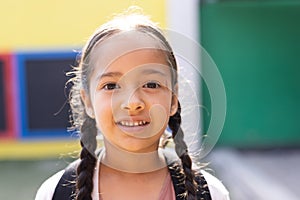 Portrait of smiling cauasian elementary schoolgirl in school playground, copy space photo