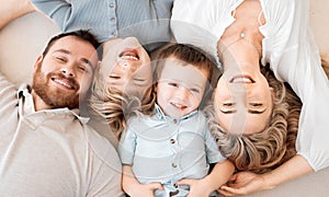 Portrait of smiling caucasian family of four from above lying and relaxing on floor at home. Faces of carefree loving
