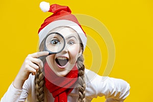 Portrait of Smiling Caucasian Girl in Santa Hat Holding Empty Big Magnifying Glass While Searching and Posing on Viewer
