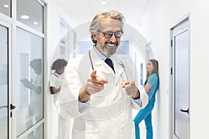 Portrait of smiling caucasian male doctor wear white medical uniform, stethoscope and glasses look at camera posing in private