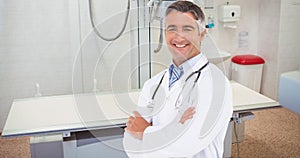 Portrait of smiling caucasian mature male doctor with arms crossed standing in hospital ward