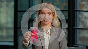 Portrait smiling Caucasian middle-aged woman hold red ribbon posing in modern office businesswoman with HIV AIDS