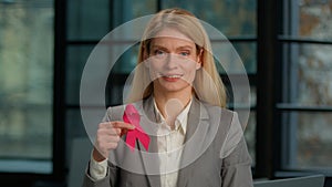 Portrait smiling Caucasian middle-aged woman in office hold red ribbon businesswoman with HIV AIDS awareness disease