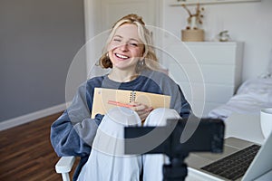 Portrait of smiling, charismatic young woman, content creator, records video on digital camera, laughing and looking