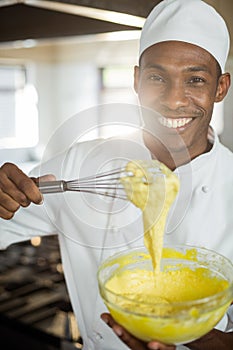 Portrait of smiling chef mixing dough