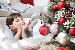 Portrait of smiling child near the christmas tree decorated with balls, comfortable in living room