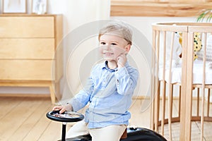 Portrait smiling  child riding toy vintage car. Funny kid playing at home. Summer vacation and travel concept. little boy driving