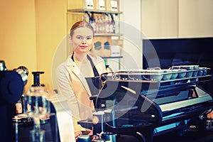 Portrait of smiling coffee shop owner standing behind counter while looking at camera