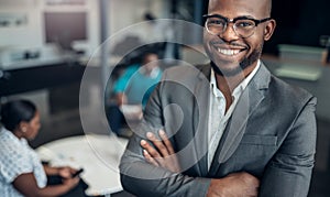 Portrait of a smiling confident black businessman with his arms crossed and all African team