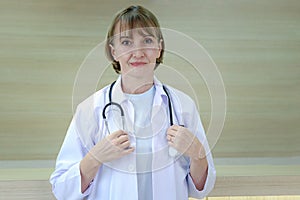 Portrait of smiling confident female doctor in white workwear holding stethoscope and standing in clinic hospital. Professional