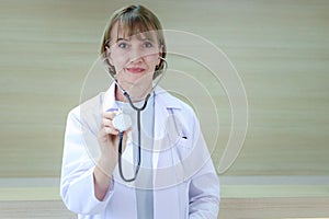 Portrait of smiling confident female doctor in white workwear holding stethoscope and standing in clinic hospital. Professional