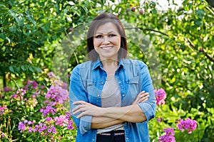 Portrait of smiling confident middle aged woman with crossed arms in garden