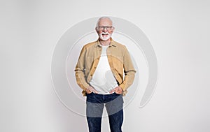 Portrait of smiling confident senior businessman with hands in pockets posing on white background