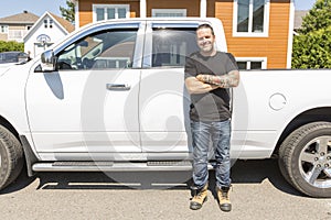 Portrait of a smiling construction worker in hardhat standing next to truck on construction site