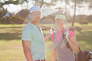 Portrait of smiling couple with bag and golf club