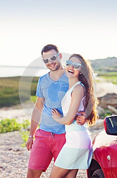 Portrait of a smiling couple with at beach by the car