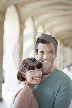 Portrait Of Smiling Couple Embracing Under Archway