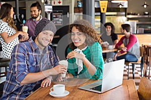 Portrait of smiling couple having milkshake while sitting in restaurant