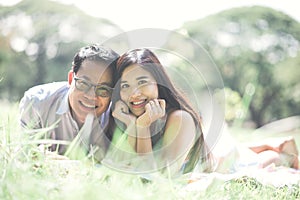 Portrait Of Smiling Couple Lying On Grassy Field At Park