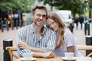 Portrait of smiling couple sitting at sidewalk cafe