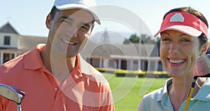 Portrait of smiling couple standing with golf club