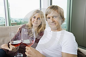 Portrait of smiling couple with wine glasses in living room at home