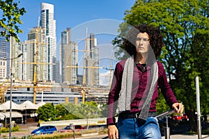 Portrait of a smiling curly haired young latino man wearing a shirt on the street. Copy space