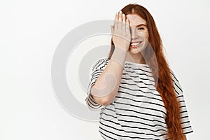 Portrait of smiling curvy woman with long natural red hair, ginger hairstyle and freckles, cover one side of face with