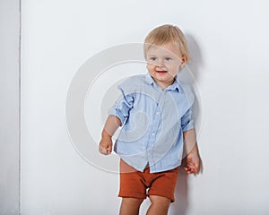 Portrait of smiling cute little boy near white wall