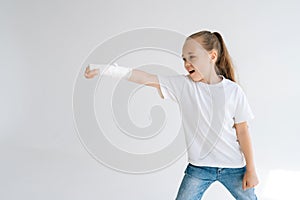 Portrait of smiling cute little girl with broken hand wrapped in white plaster bandage playing gesturing with injured