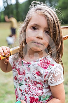 Portrait of smiling cute little girl playing with an old tennis racket in a public park