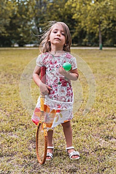 Portrait of smiling cute little girl playing with an old tennis racket