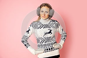 Portrait of smiling cute pretty woman 30-35 years in earmuffs. Studio shot on pink background. Concept of personal