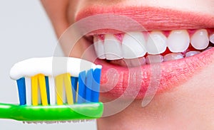 Portrait of a smiling cute woman holding toothbrush. Close up of perfect and healthy teeth with toothbrush. Smiling