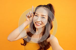 Portrait of a smiling cute woman making selfie photo on smartphone isolated on a yelllow background photo