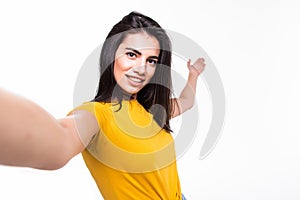 Portrait of a smiling cute woman making selfie photo on smartphone on a white background